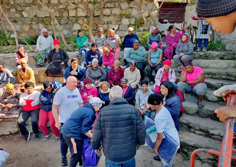 Community members of all ages gathered on outdoor steps at a Salt and Light Foundation outreach
