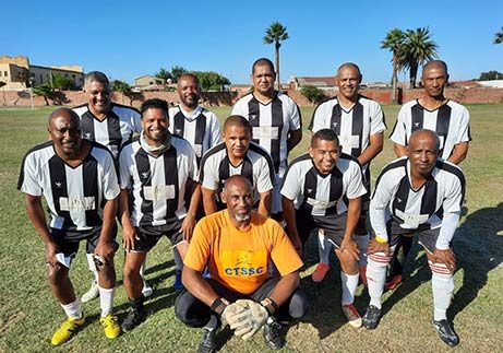 ENS FC players in black-and-white striped kit posing as a team on a football field