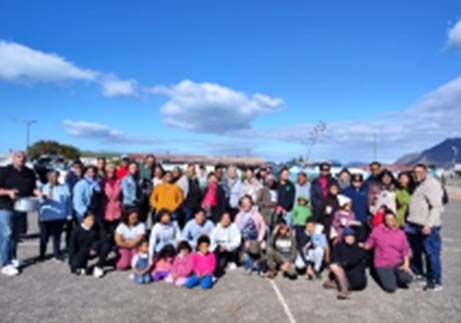 A large group of Salt and Light volunteers and community members outdoors under a blue sky