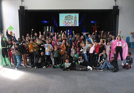A large group of children, young people and volunteers celebrating together in a hall